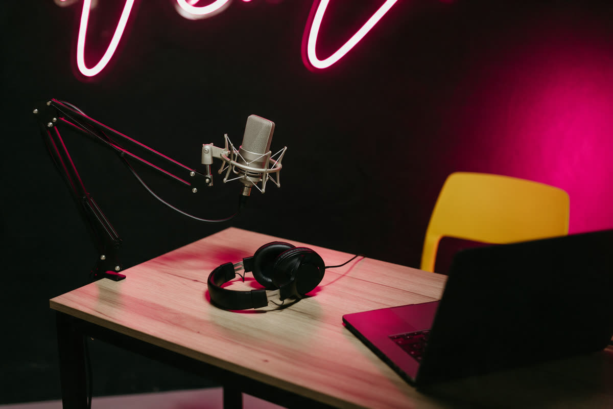 Podcast studio with a microphone on a boom arm under pink neon light